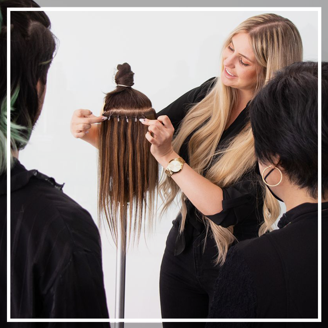 Instructor giving hair extension application lesson