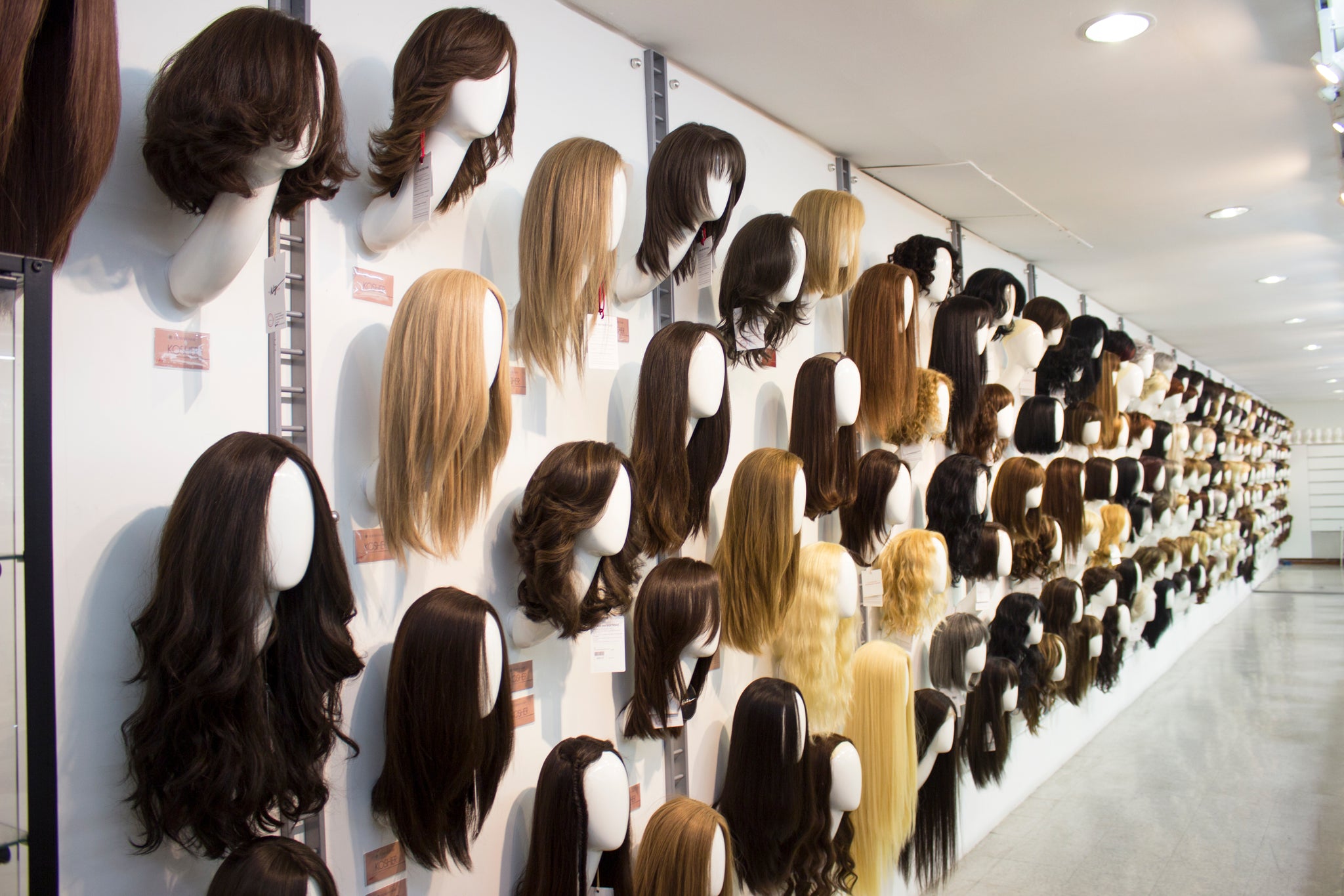 A large wall display of wig heads wearing wigs in different colors
