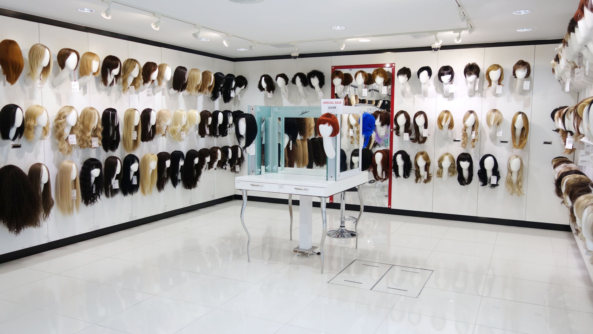 Display of wigs on mannequin heads along the walls