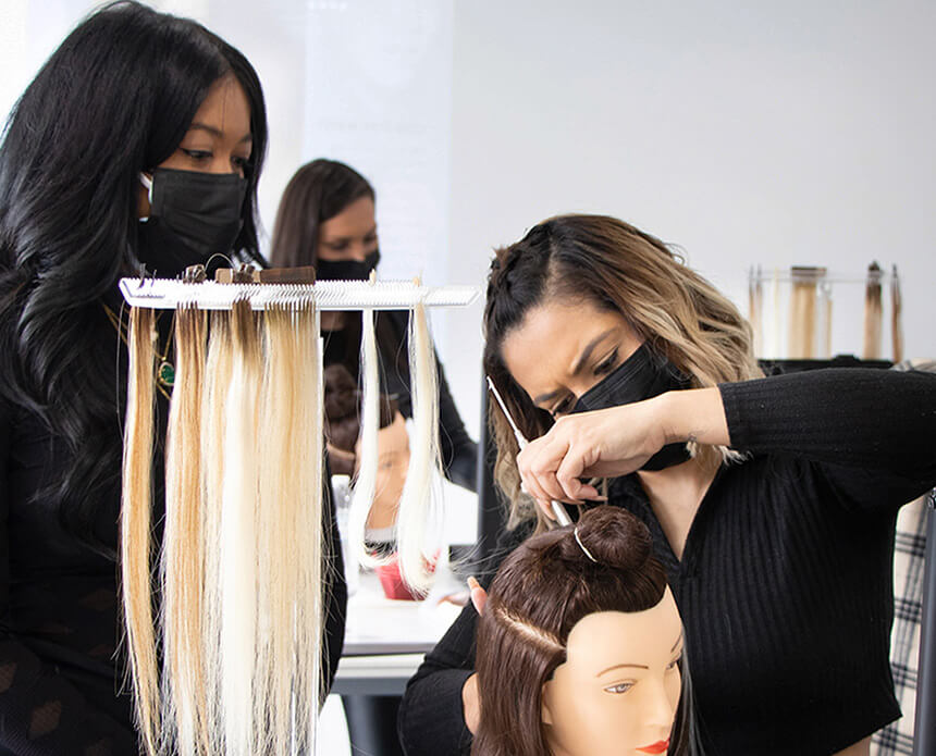 A student learning how to apply extensions to a wig head 